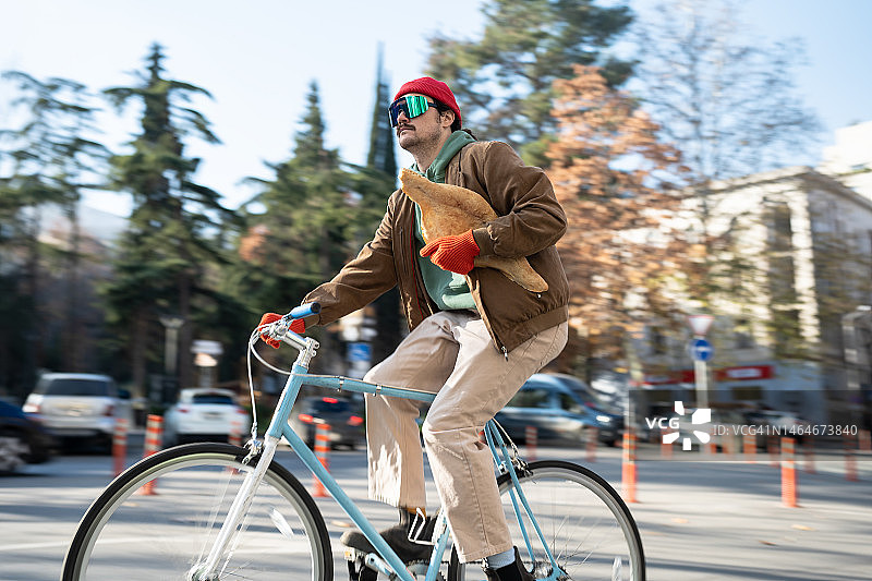 骑自行车从面包店运送新鲜面包的年轻格鲁吉亚男子图片素材