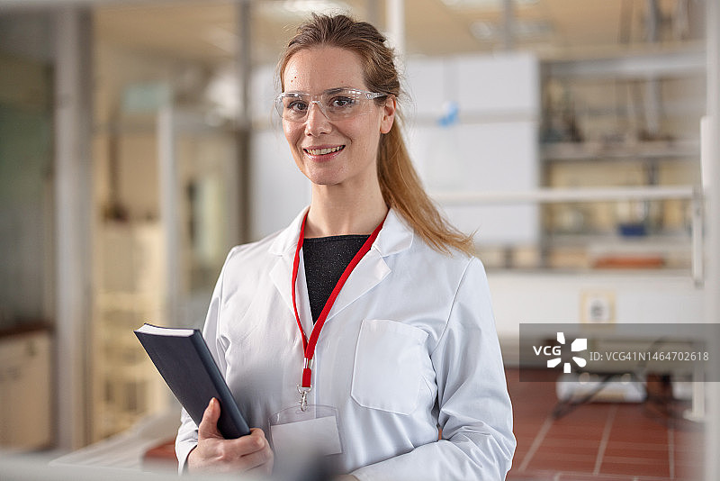 身穿实验服和防护眼镜的自信白人女实验员肖像图片素材