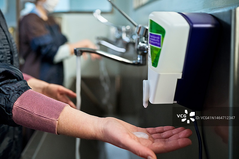 女外科医生的手在医院的水槽皂液器下图片素材