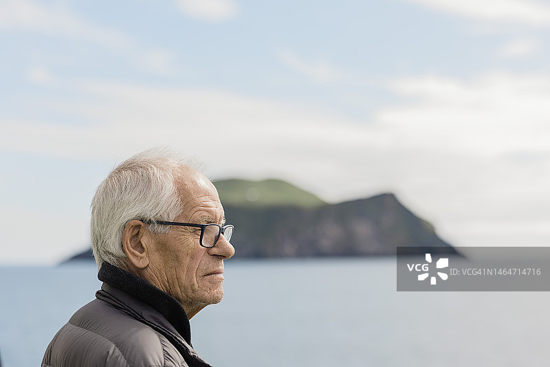 背景是海岛的老年男人侧面照图片素材