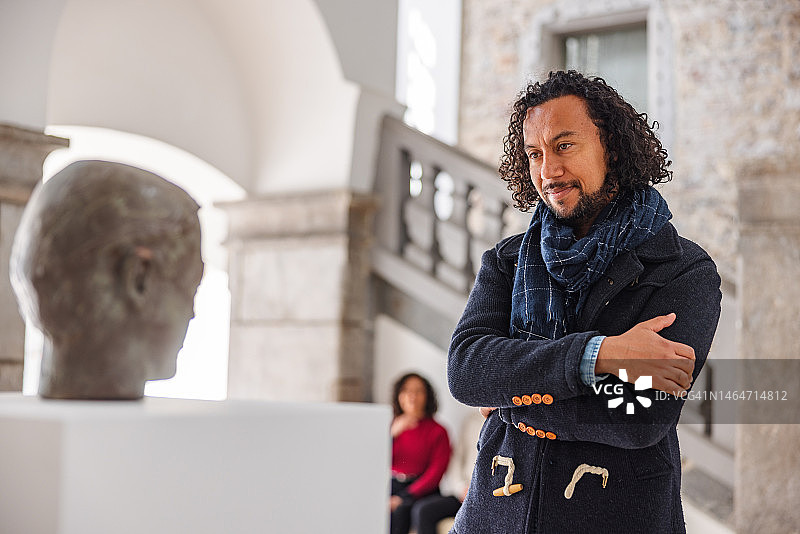成年黑人男性历史爱好者在博物馆里微笑地看着雕像图片素材
