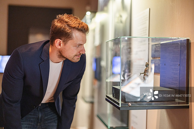 在博物馆观看小型雕像的迷人白人成年男子图片素材