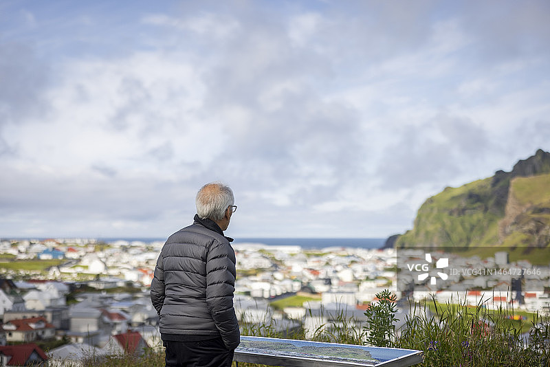 在冰岛西人群岛看小镇地图的活力老年男性图片素材