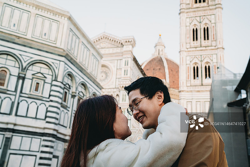 一对相爱的亚洲情侣在意大利佛罗伦萨的圣玛丽亚·德尔·菲奥里广场上接吻图片素材