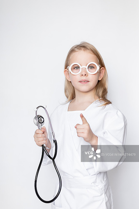 穿着医生服装、戴着眼镜的小女孩拿着听诊器（乌克兰，基辅）图片素材