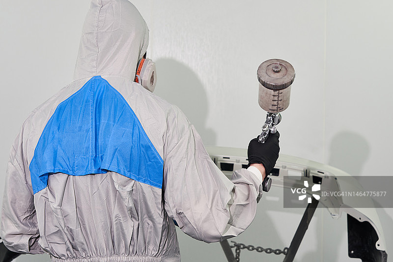 修理工在喷漆房用喷枪喷涂汽车保险杠图片素材