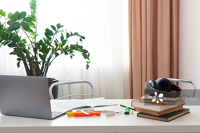 空旷的工作场所，办公桌上有笔记本电脑和书籍，室内设计图片素材