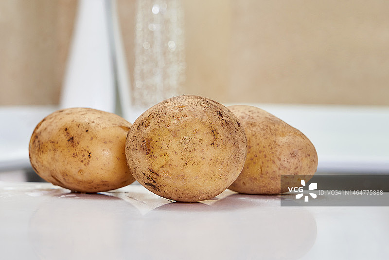 准备烹饪的、放在水槽附近的湿土豆图片素材