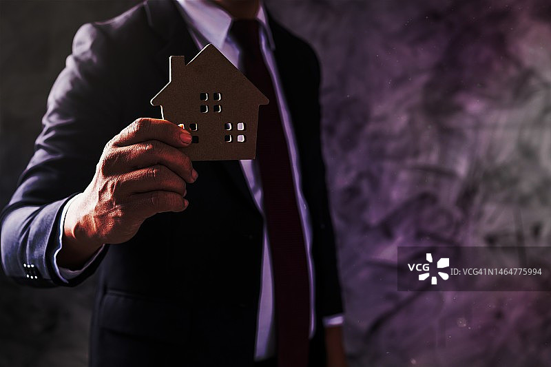 持有房屋模型以展示出租的商人或银行职员图片素材