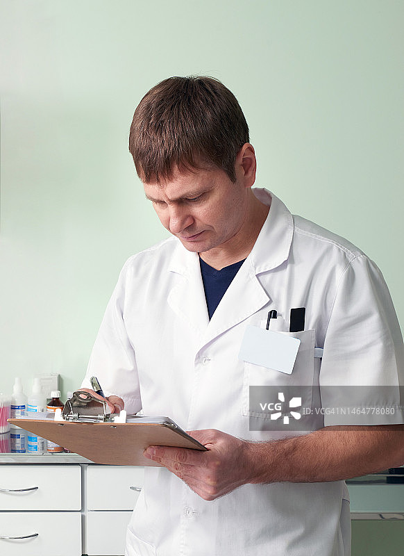 穿着白大褂的医生在他的办公室里拿着写字板图片素材