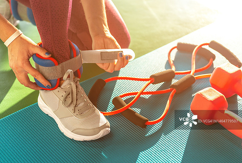 女人在健身房锻炼前戴上脚踝负重图片素材