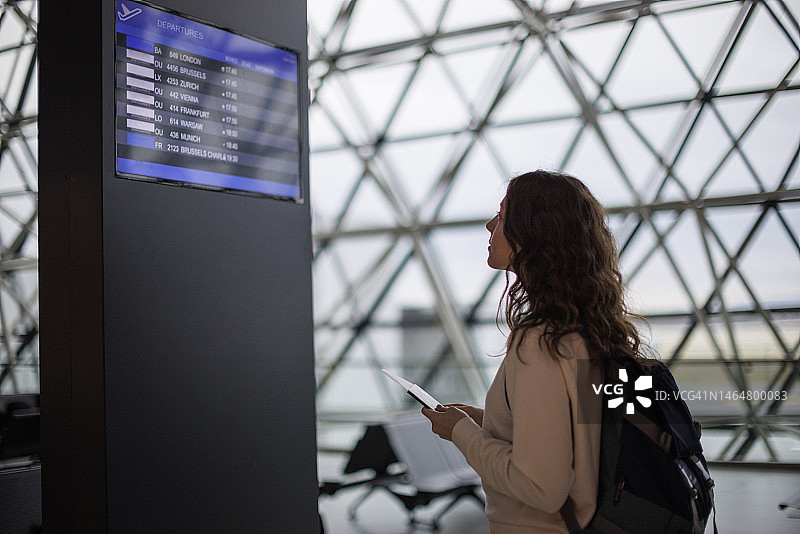 在机场查看到达/离开显示屏的少女图片素材