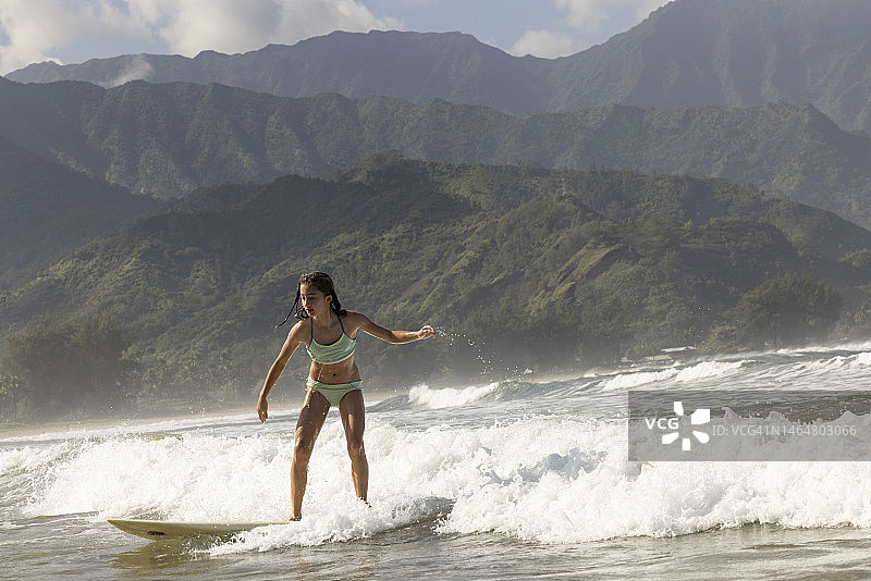 年轻女孩在夏威夷考艾岛哈纳雷海湾冲浪图片素材