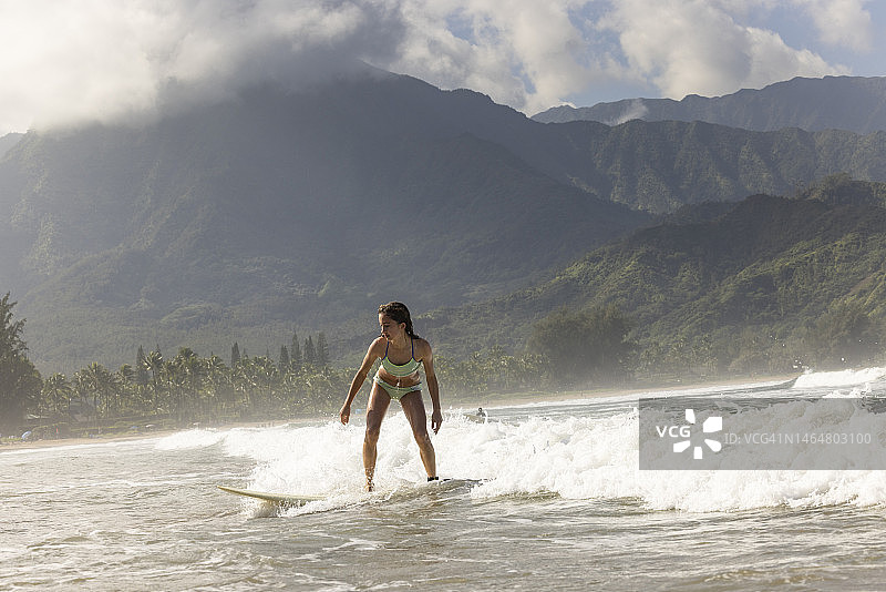 年轻女孩在夏威夷考艾岛哈纳雷海湾冲浪图片素材