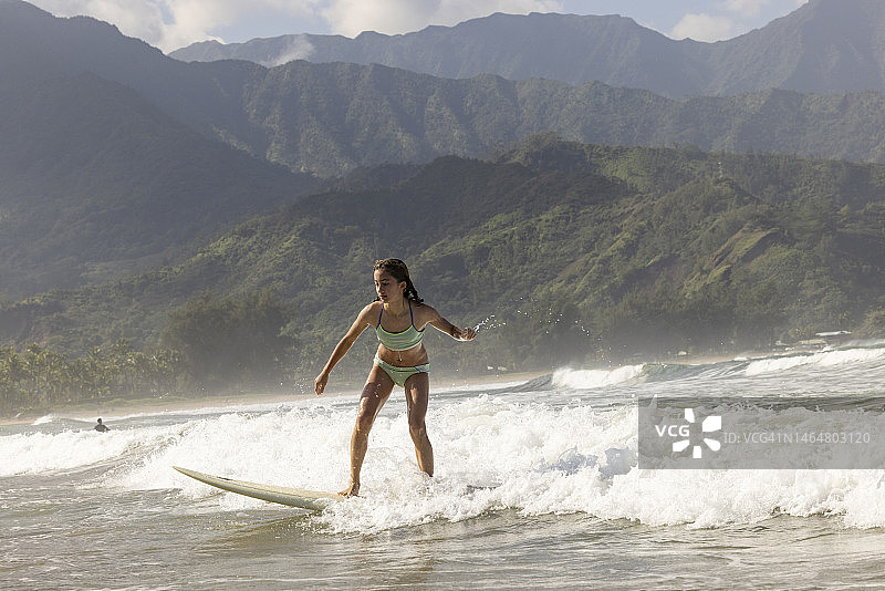 年轻女孩在夏威夷考艾岛哈纳雷海湾冲浪图片素材