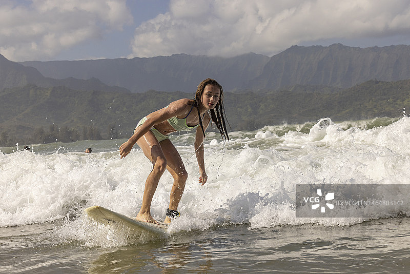 年轻女孩在夏威夷考艾岛哈纳雷海湾冲浪图片素材