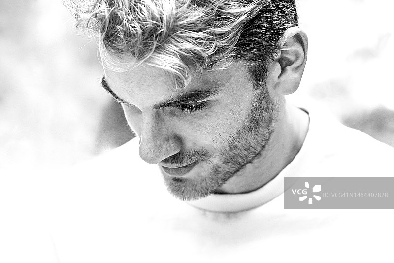 有空白背景的向下看的年轻男人的黑白肖像照图片素材