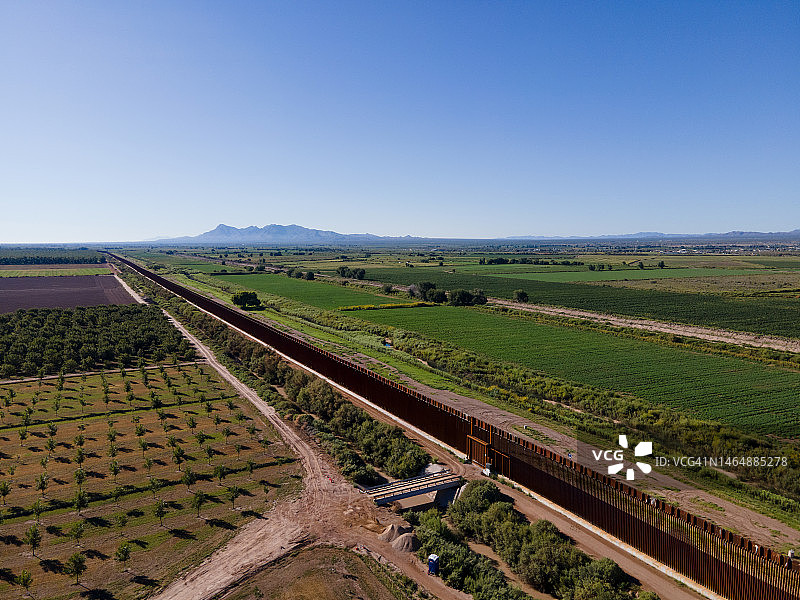 奇瓦瓦墨西哥和德克萨斯州汉考克堡之间的边境墙，阳光明媚的午后有果园和农田图片素材