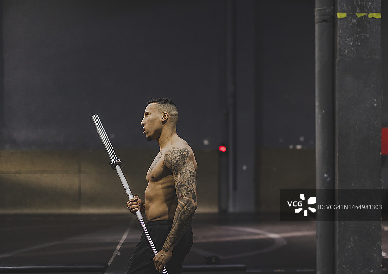 在健身房锻炼后举起杠铃的健壮西班牙裔男人图片素材