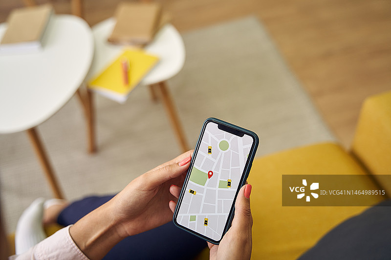 女子使用手机搜索出租车的应用程序，拍摄其手部的俯视图图片素材