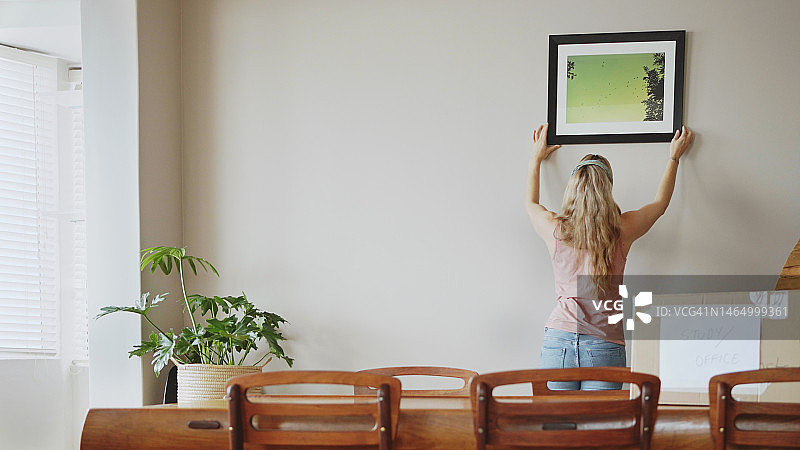 女性在新家墙上挂画图片素材