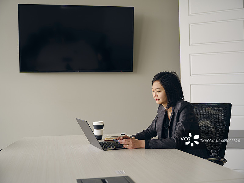 在办公室使用笔记本电脑和智能手机的女人图片素材