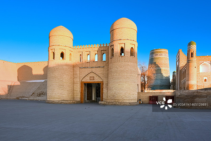 黄昏时分乌兹别克斯坦希瓦古城伊钦卡拉的壮丽景色,彩色卡尔塔米诺尔塔、西门和穆罕默德·阿明汗伊斯兰教学校图片素材