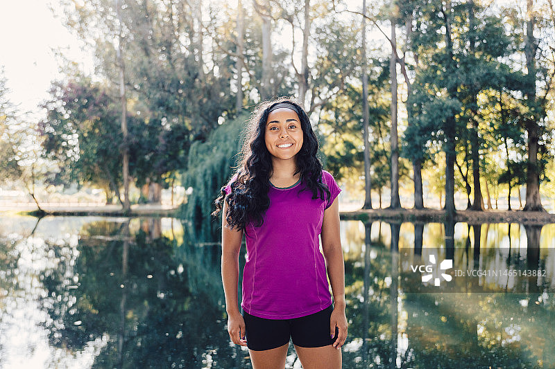 在泻湖旁的公园里即将开始训练的微笑的年轻本土马普切赛跑女运动员 портрет图片素材