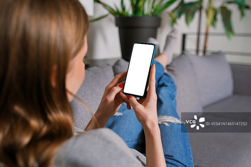 女人在家用智能手机白色屏幕样机图片素材