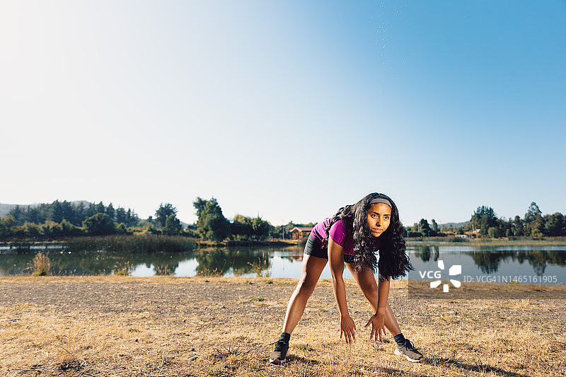 年轻拉美越野跑步女人训练前在泻湖旁拉伸腿部肌肉图片素材