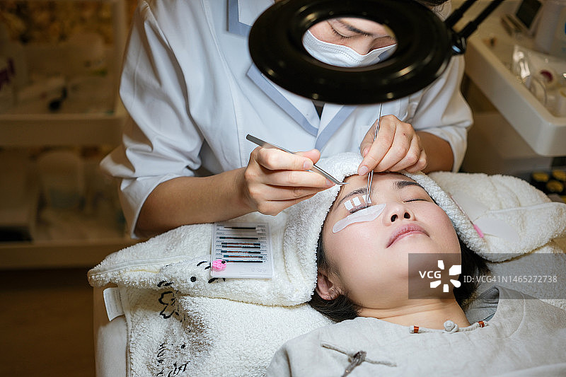 美容师为顾客嫁接假睫毛图片素材