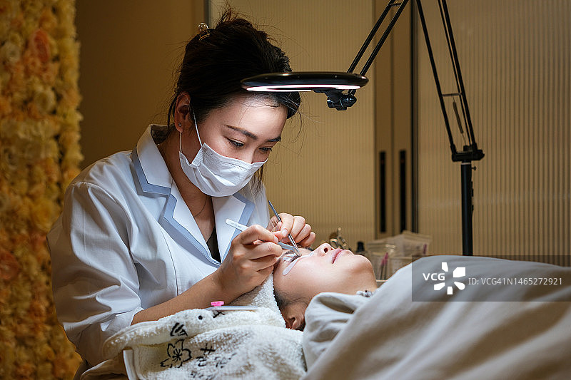 美容师为顾客嫁接假睫毛图片素材