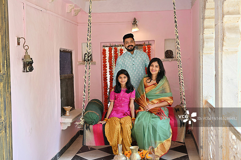 穿着传统服饰坐在秋千上看向镜头的印度家庭图片素材