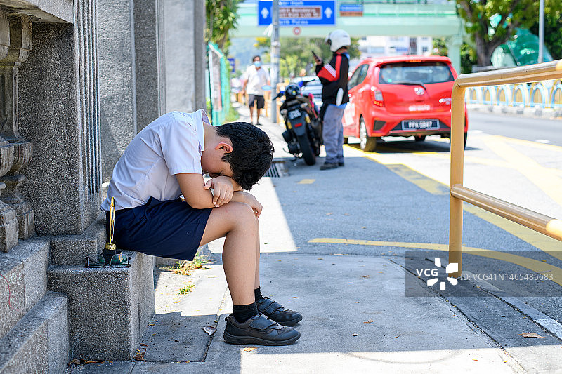 学生坐在砖墙上感到疲倦图片素材