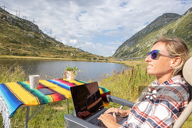 坐在露营椅上，用笔记本电脑在户外远程工作的女人图片素材