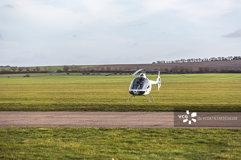 黄昏时停在机场草地上的小型直升机图片素材