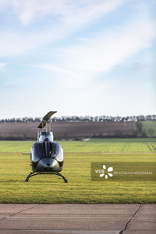 黄昏时停在机场草地上的直升机图片素材