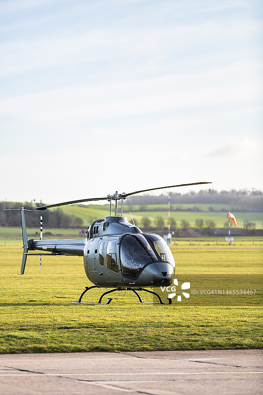 黄昏时停在机场草地上的直升机图片素材