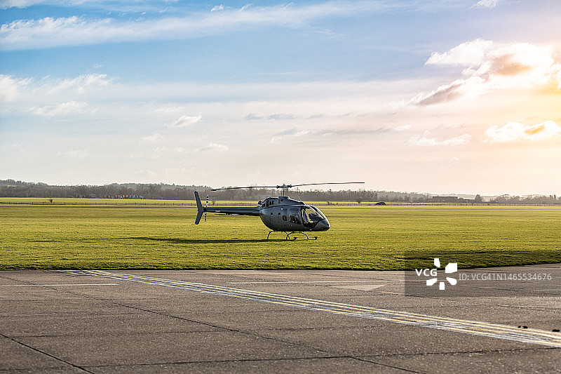 黄昏时停在机场草地上的直升机图片素材