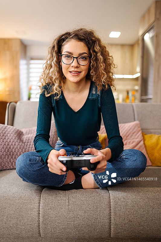 年轻女人在客厅里玩电子游戏图片素材