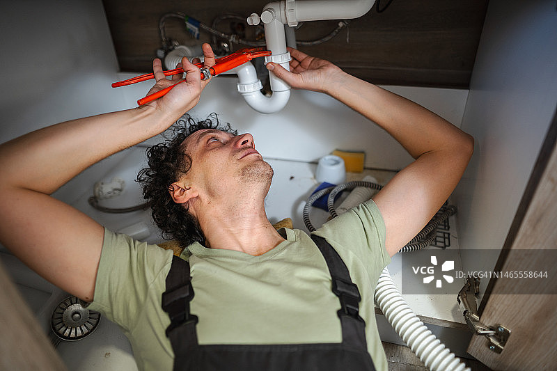 水管工维修厨房水槽下的水管图片素材