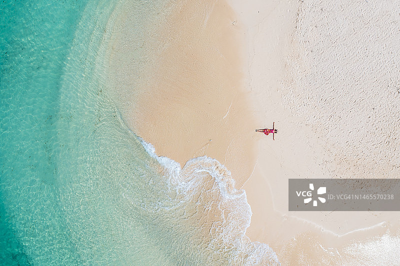 航拍：女子躺在海岸线上图片素材