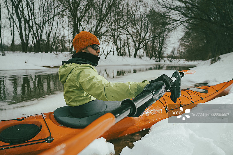 男人在冰冷的河流上划皮划艇图片素材