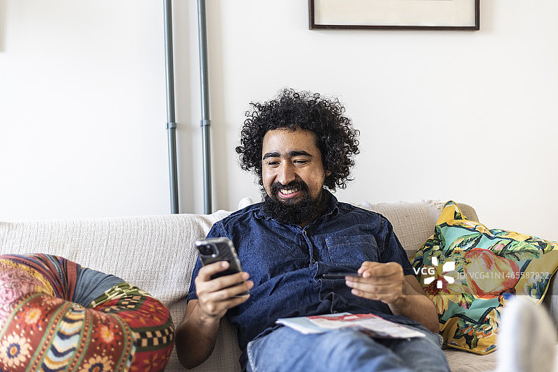 快乐的黑人使用信用卡和手机支付账单图片素材