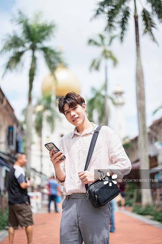 在新加坡城市苏丹清真寺附近使用智能手机的游客男人的背影图片素材