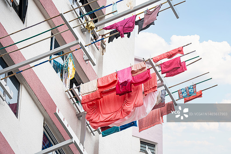 建筑物外窗户上悬挂晾晒的粉色衣服图片素材