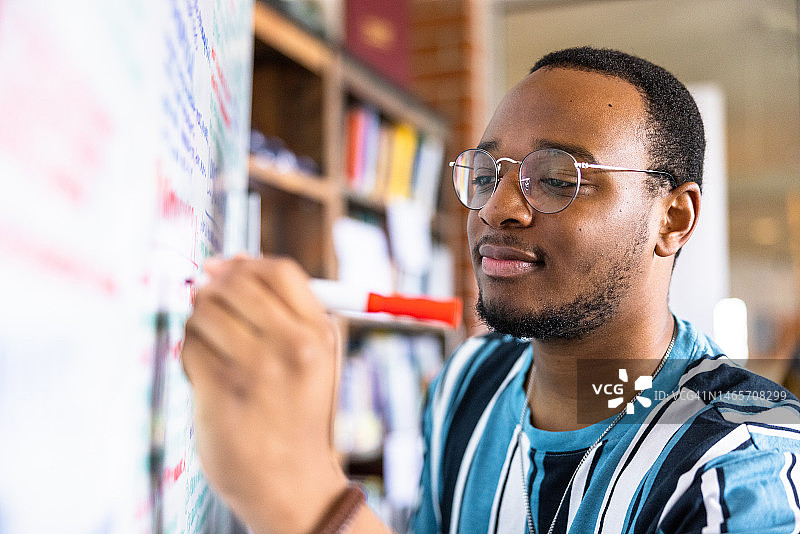 在白板上写笔记的年轻黑人男大学生图片素材
