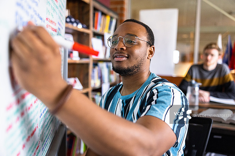 在白板上写笔记的年轻黑人男大学生图片素材