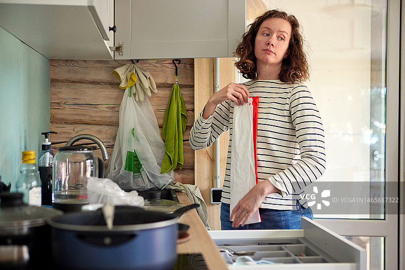 拿毛巾的女人站在厨房柜台附近图片素材
