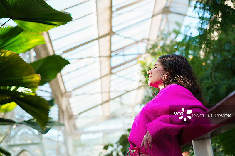 穿着粉色时装的年轻女模特在自然背景下的侧面像图片素材